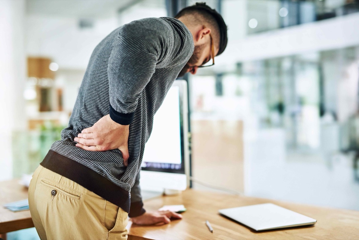 Man experiencing back pain at his office desk